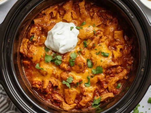 A close-up view of a bubbling crockpot chicken enchilada casserole, ready to serve.