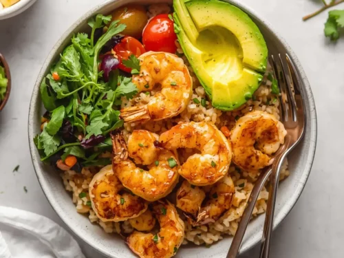 A vibrant grilled shrimp and brown rice buddha bowl filled with fresh vegetables