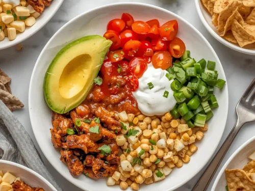 A healthy crockpot chicken burrito bowl topped with avocado and cilantro.