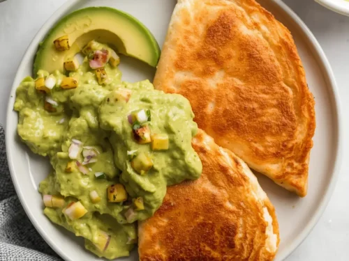 A serving of shrimp quesadillas with a side of fresh avocado salsa.