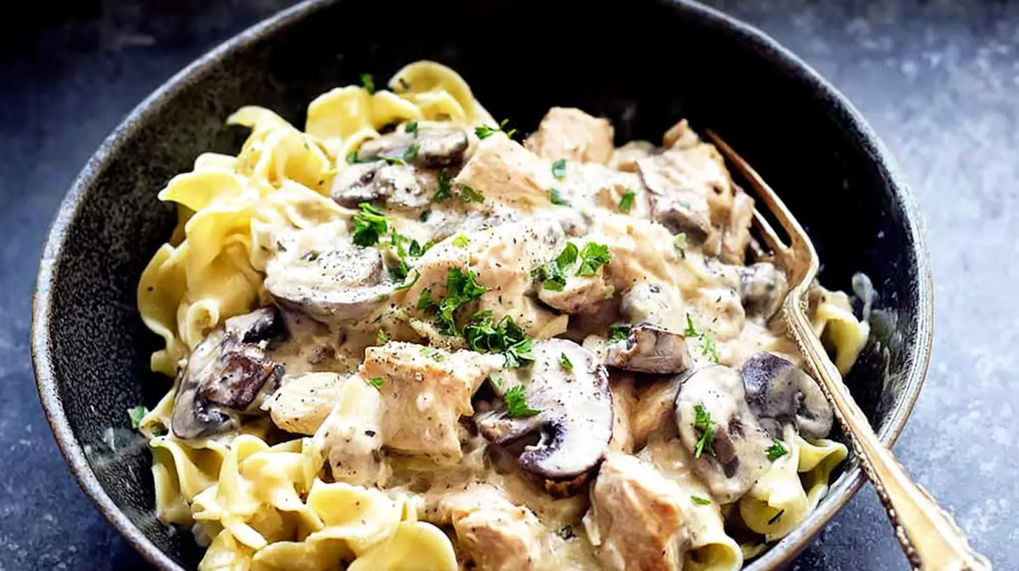 A serving of easy crockpot chicken stroganoff in a bowl with egg noodles