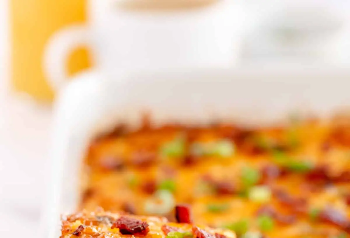 An uncooked breakfast casserole ready to be baked, showing various ingredients layered.