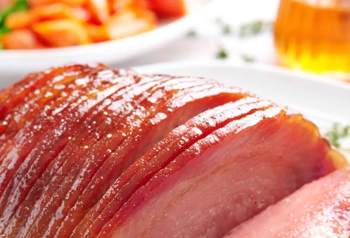A perfectly cooked honey glazed ham, sliced and ready to serve.