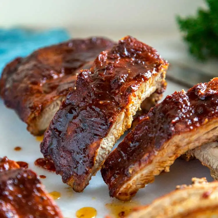 A platter of glistening Kansas City ribs with a thick BBQ sauce