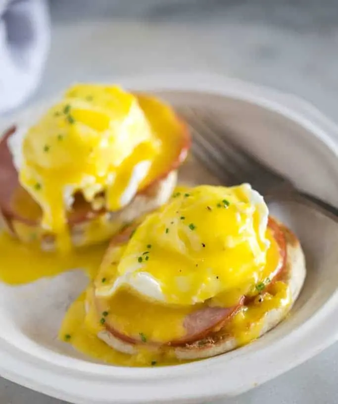 A close-up shot of perfectly poached eggs benedict with hollandaise sauce