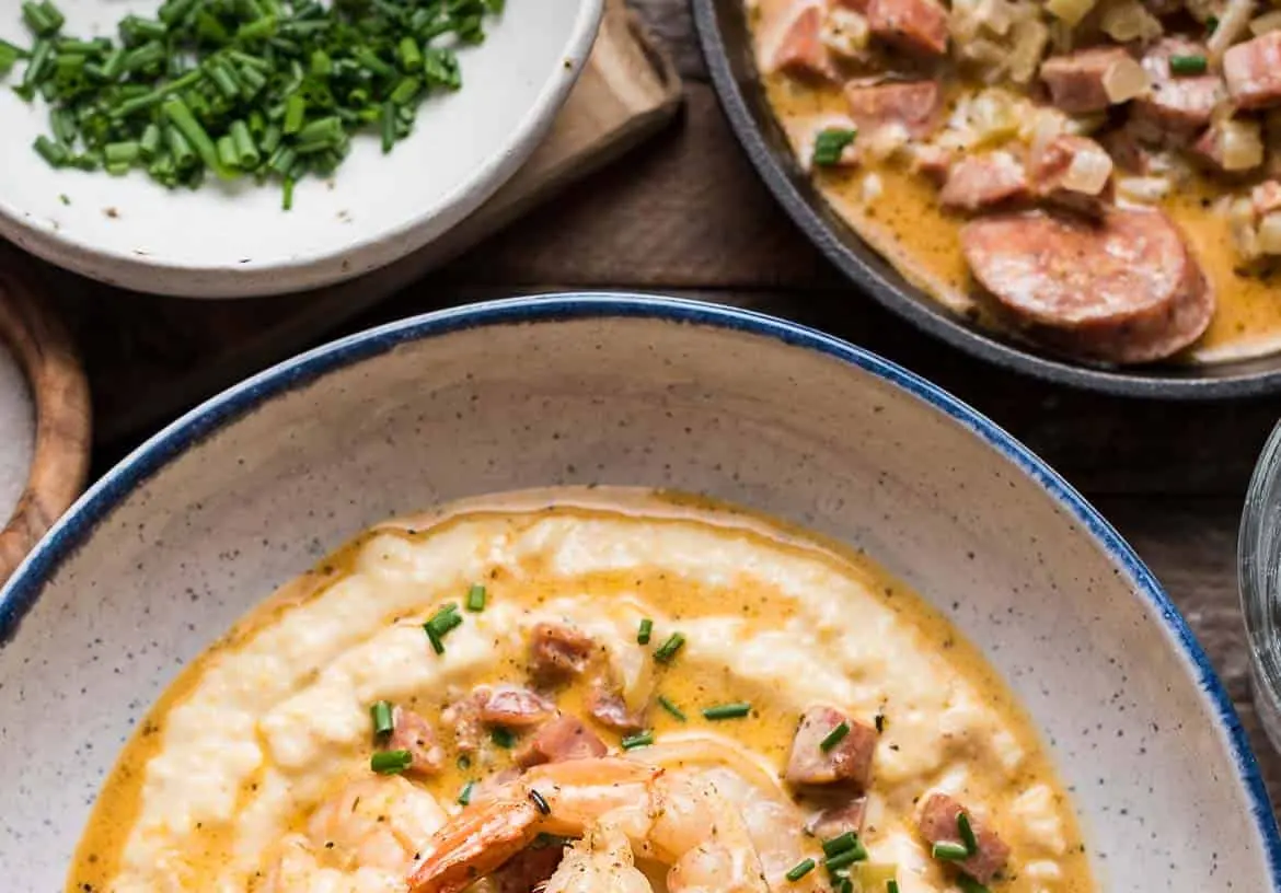 A plate of shrimp and grits garnished with fresh herbs