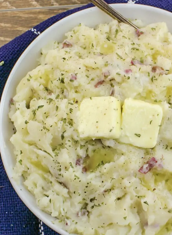 A bowl of creamy southern mashed potatoes garnished with herbs