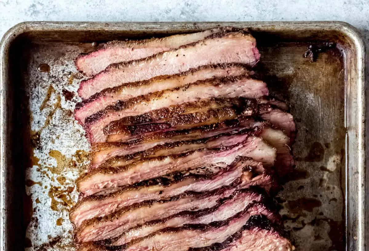 A perfectly cooked Texas smoked brisket with a deep bark and juicy interior, sliced on a cutting board.